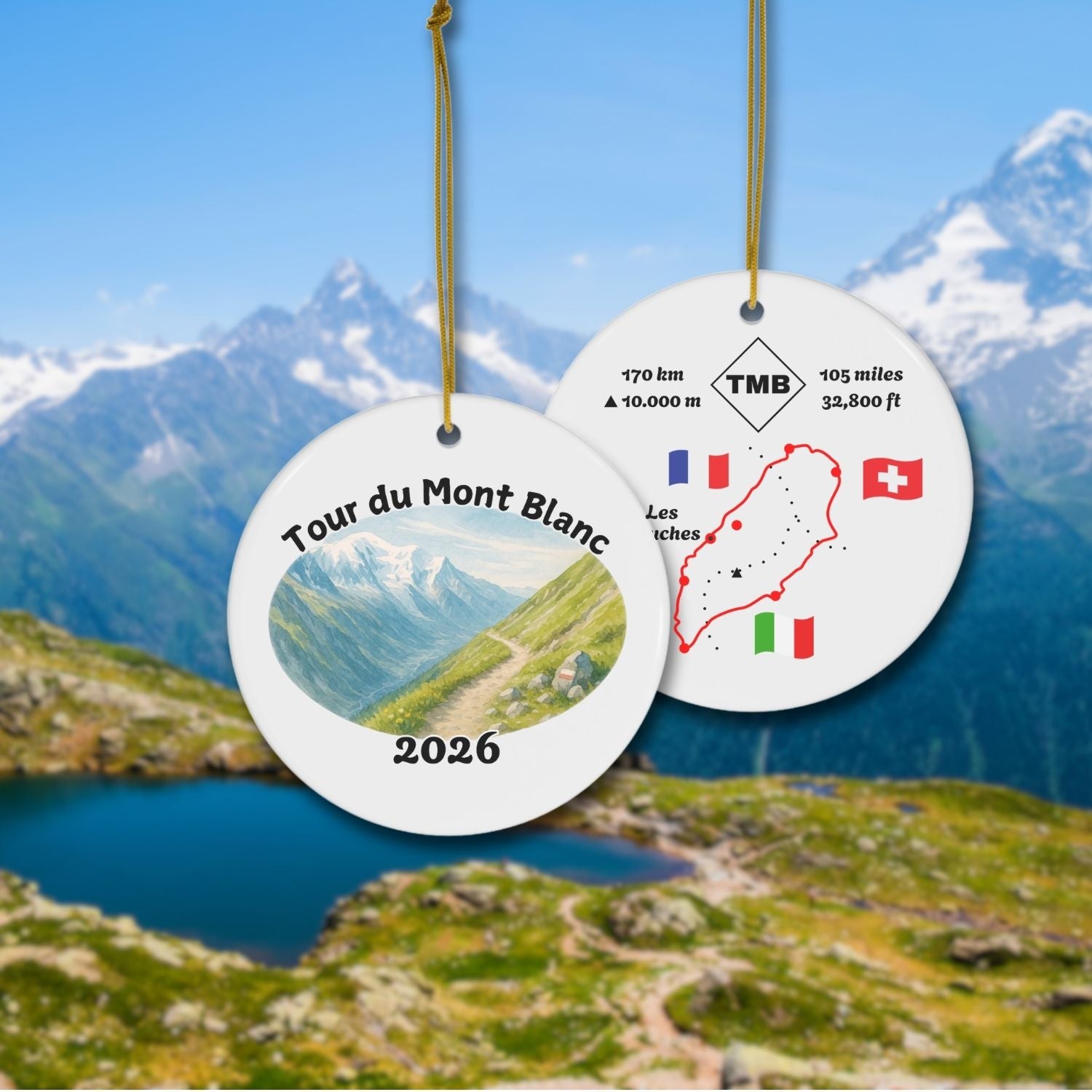 Tour du Mont Blanc ceramic keepsake ornament showing watercolor trail scene on the front and stylized TMB map with distance and flags on the back, displayed on an alpine background.