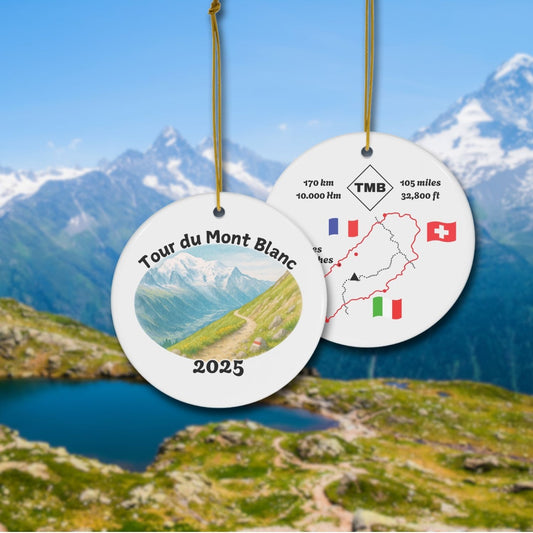 Tour du Mont Blanc ceramic keepsake ornament showing watercolor trail scene on the front and stylized TMB map with distance and flags on the back, displayed on an alpine background.
